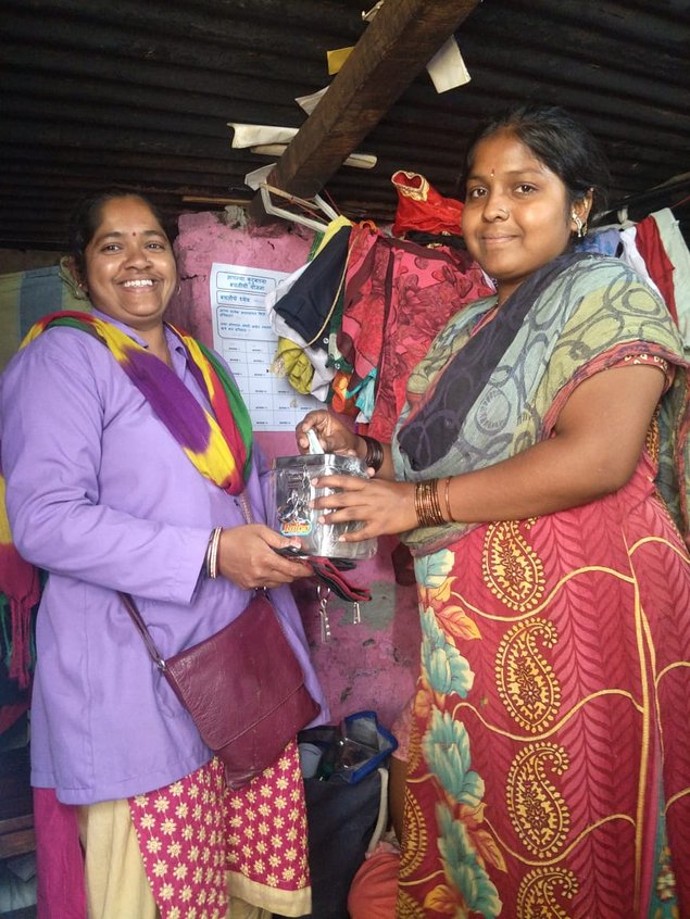 female project partner hands over a savings box to another woman