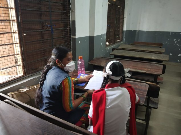 Female enumerator interviews a female particpant in a school.