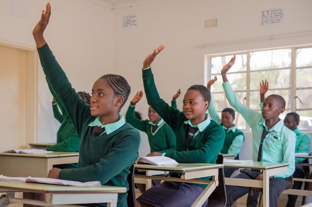 Pupils in a Zambian school raining their hands in a classroom