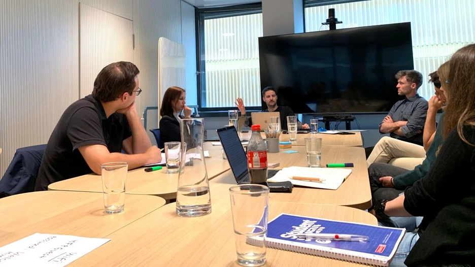 The participants of the workshop sit around a conference table discussing Vincent's ideas on Egalitarian Corporatism and the Problem of Oligarchy